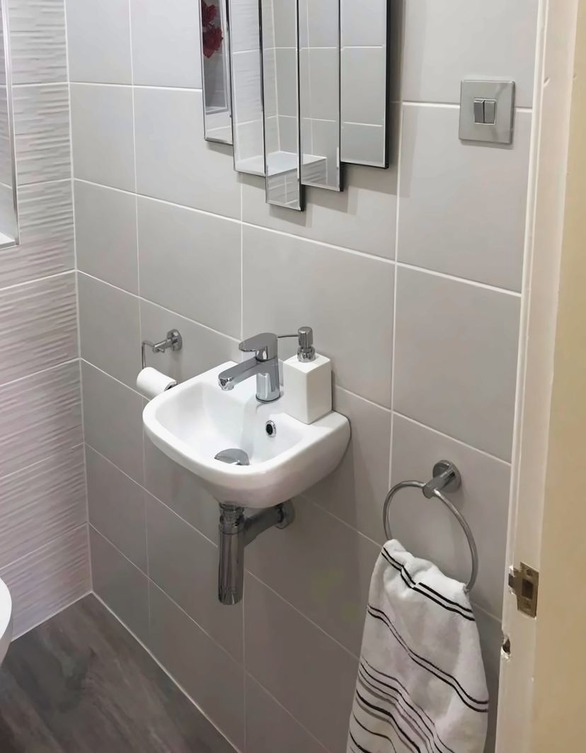 Cloakroom with a corner basin, a mirror and a towel ring