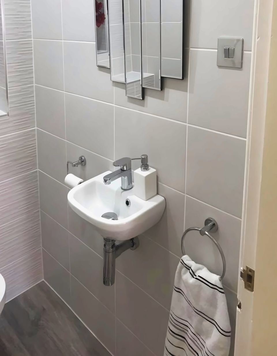 Cloakroom with a corner basin, a mirror and a towel ring