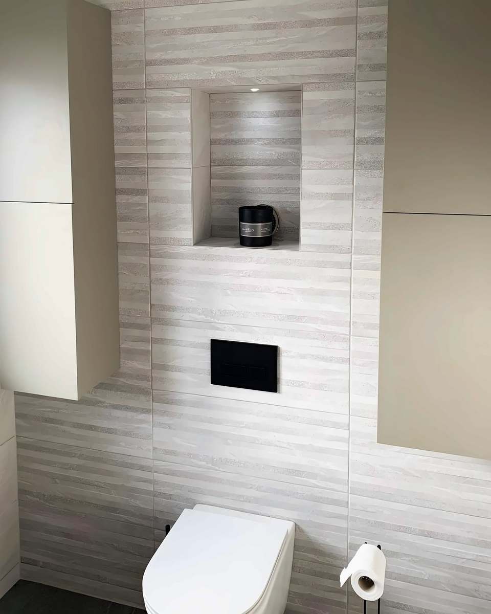 Wall-hung toilet with a concealed cistern, a tiled niche and tall wall units