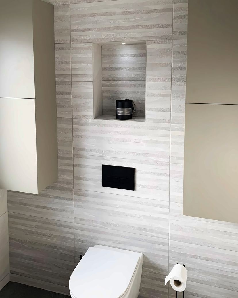 Wall-hung toilet with a concealed cistern, a tiled niche and tall wall units