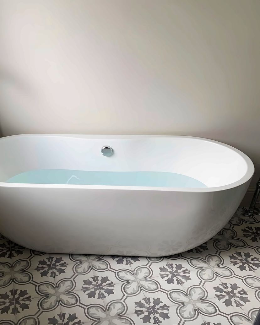 Freestanding bath with a floor-standing mixer tap on patterned floor tiles