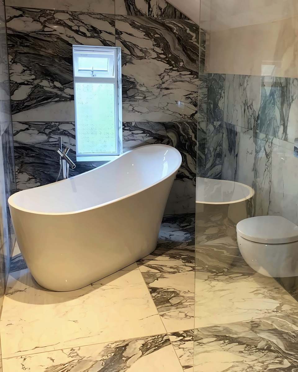 Marble-effect bathroom with a slipper bath under the window and a wall-hung toilet