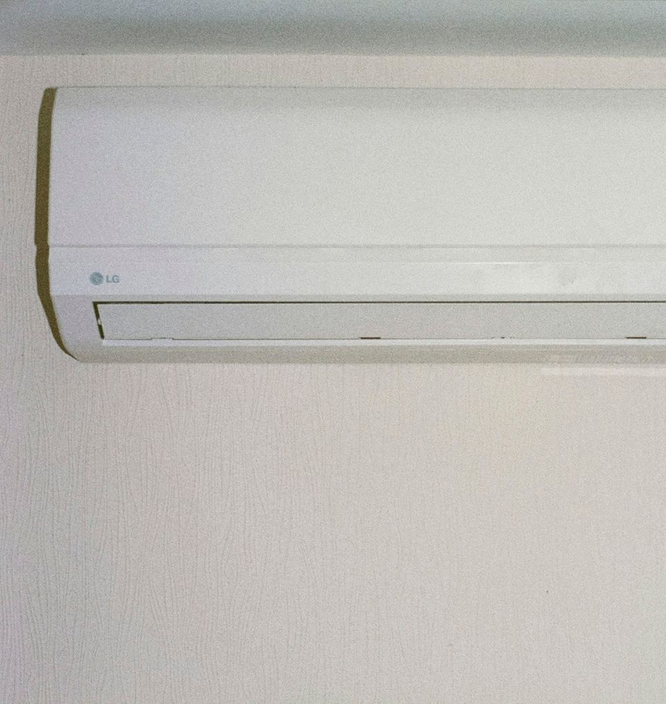 White wall-mounted air conditioning unit with its pipe cover running down the wall